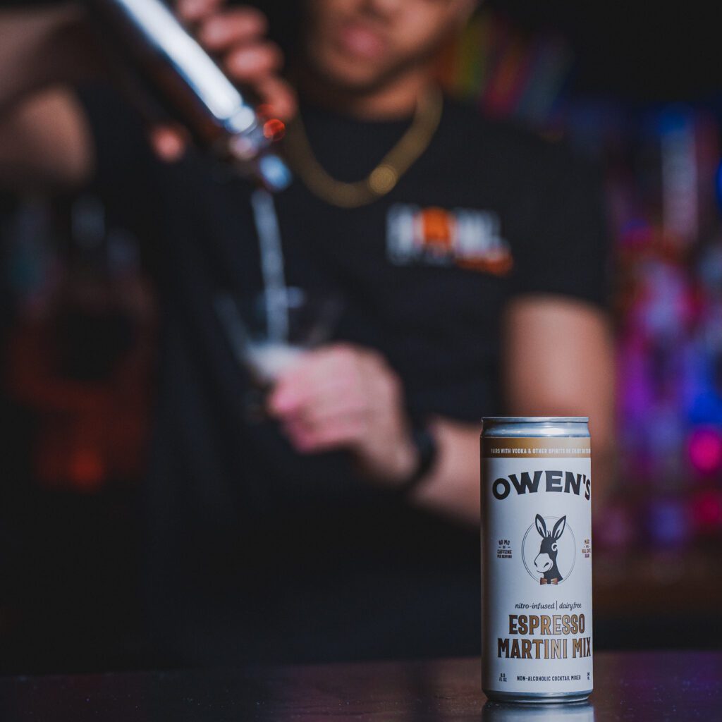 Bartender pouring a polar espresso shot featuring a close up view of Owen's Nitro Infused Espresso in a can